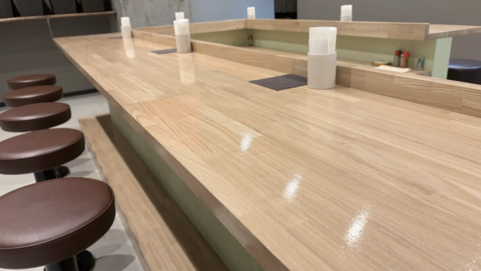 寅乃虎の店内。明るい木のカウンターと焦げ茶の丸椅子が並ぶ