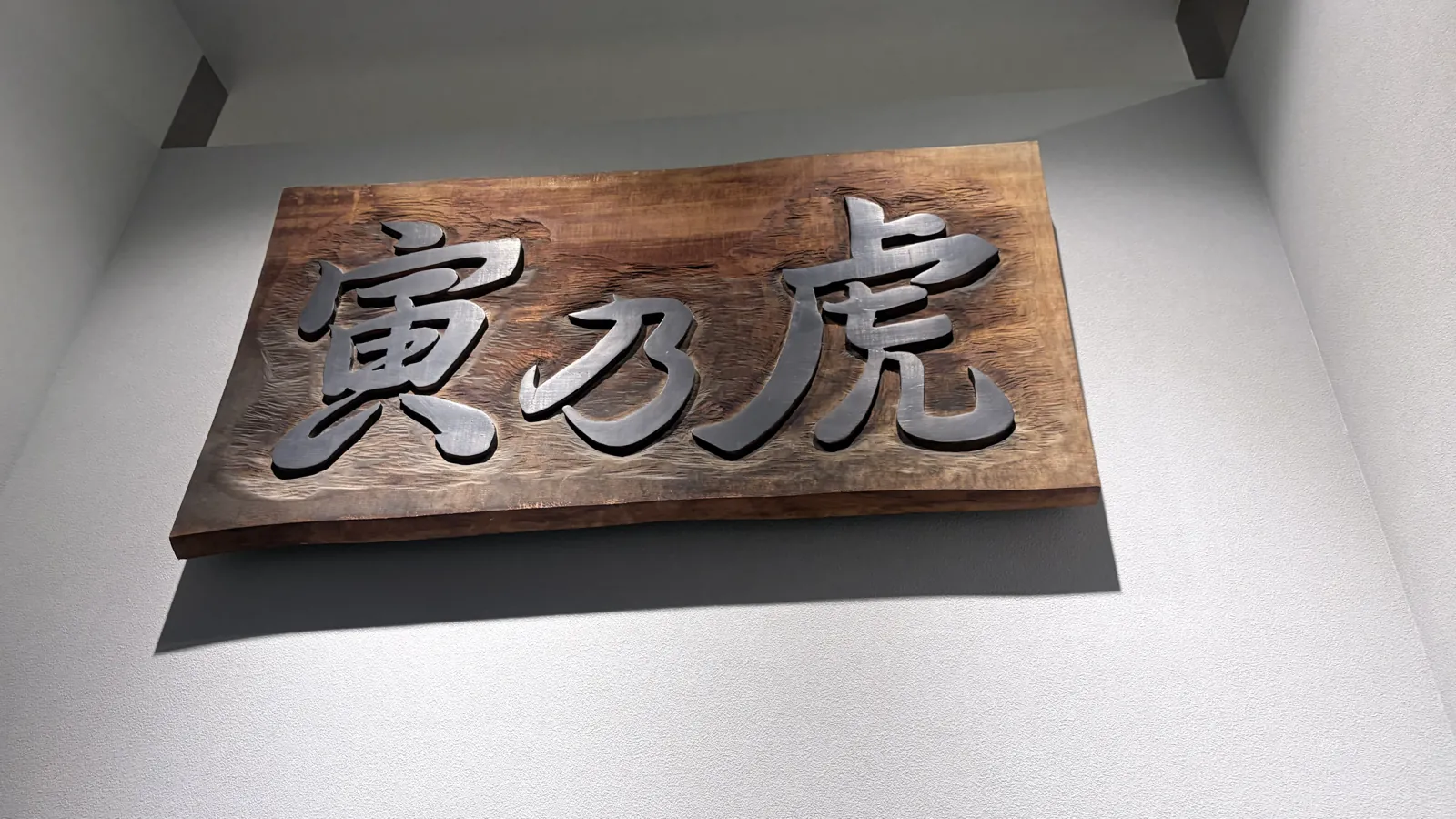 店内に掲げられた寅乃虎の木製看板。一枚板に立体的な文字が彫られている