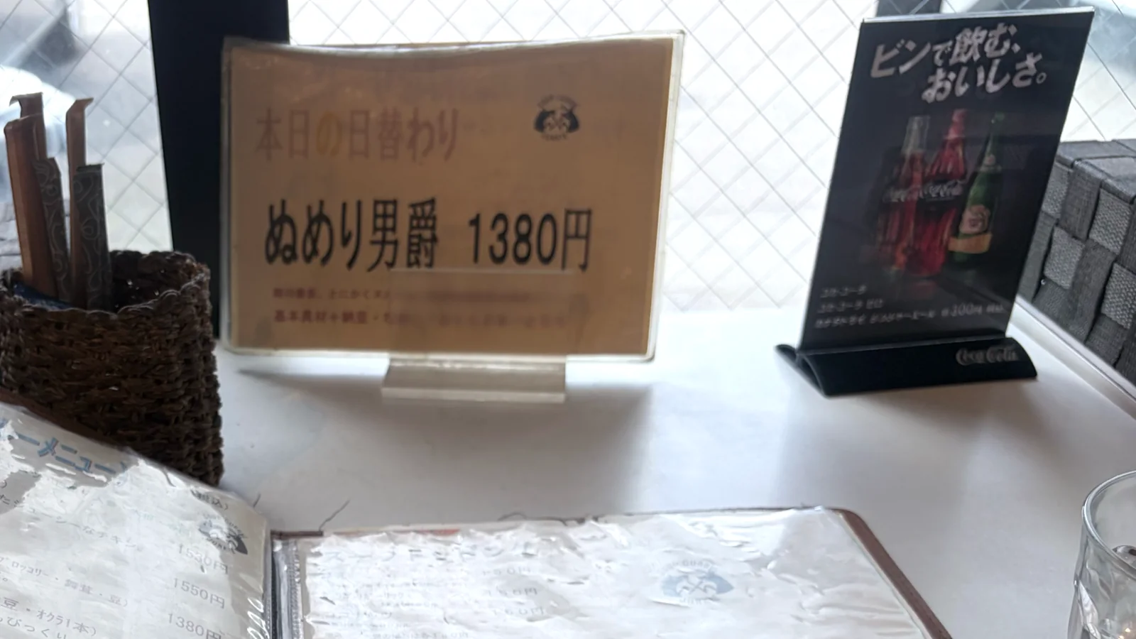 ひげ男爵の窓際のカウンター席。卓上にメニューと日替わりの案内が置かれている