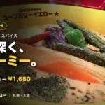 スープカリーイエローのチキン野菜カリー。黄色い器にクリーミーなスープと赤唐辛子やオクラなどの野菜が並ぶ